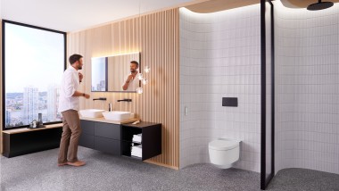 Homme dans une salle de bains devant le miroir Geberit Option Plus Square et des meubles de salle de bains Geberit ONE noirs (© Geberit)