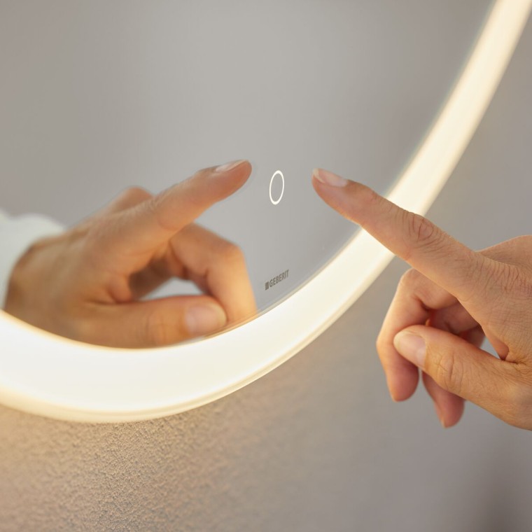 Interrupteur sensitif à commande manuelle sur le miroir Geberit Option Round (© Geberit) Interrupteur sensitif à commande manuelle sur le miroir Geberit Option Round (© Geberit)