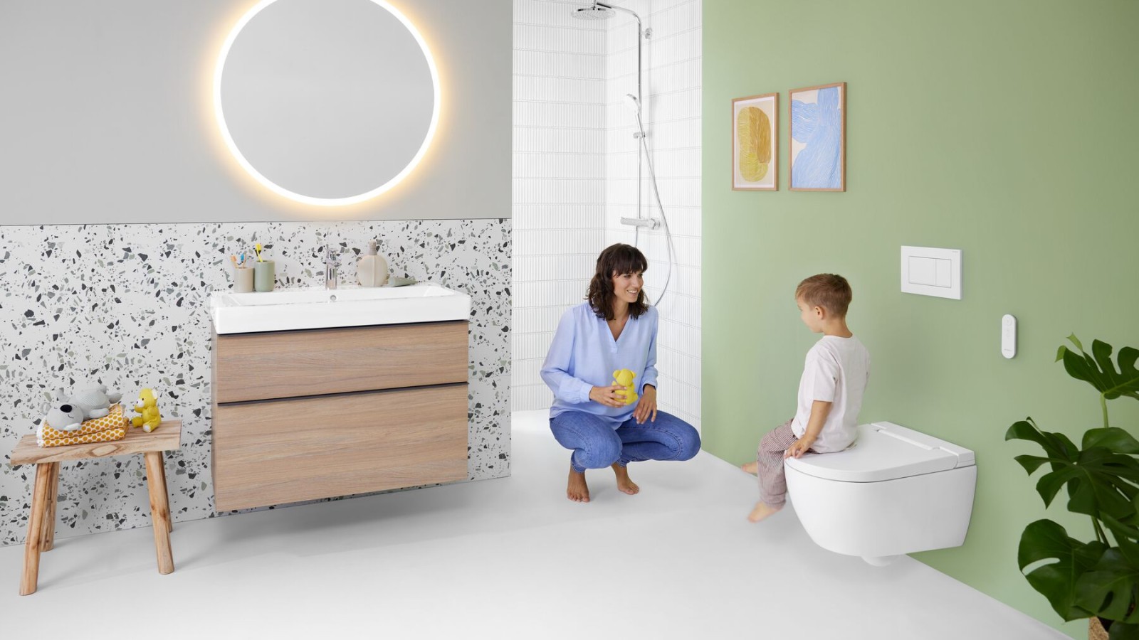 Une femme et un enfant dans une salle de bains avec un WC lavant Geberit AquaClean Alba Une femme et un enfant dans une salle de bains avec un WC lavant Geberit AquaClean Alba