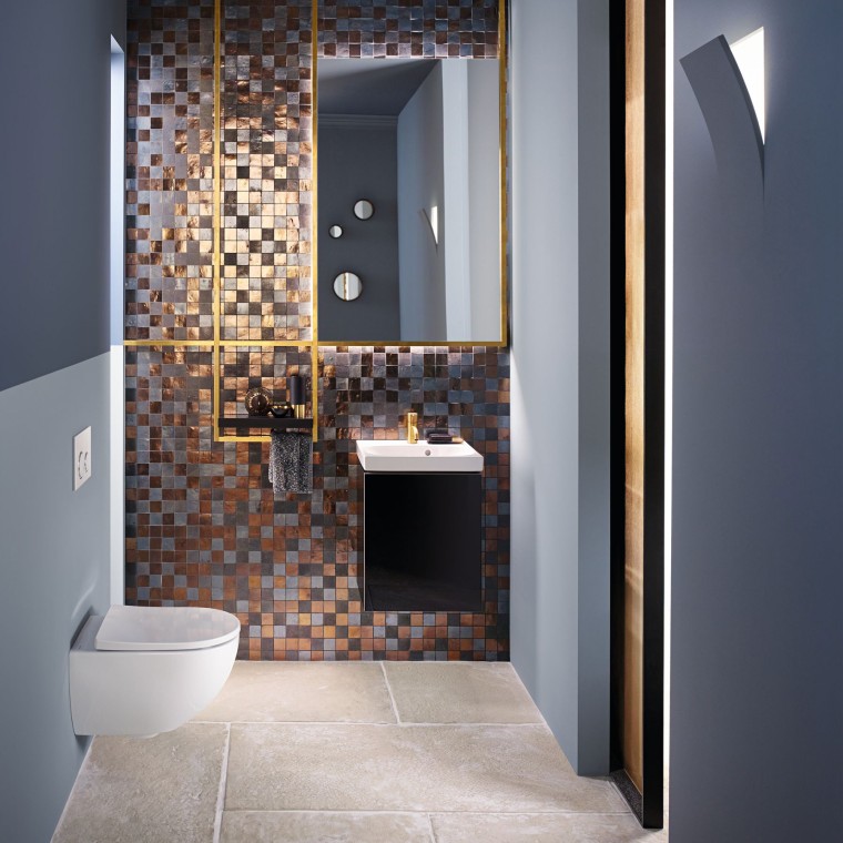 Salle de bains d’invités moderne dotée d’un WC et d’un lavabo Acanto placé devant un panneau en mosaïque. Salle de bains d’invités moderne dotée d’un WC et d’un lavabo Acanto placé devant un panneau en mosaïque.