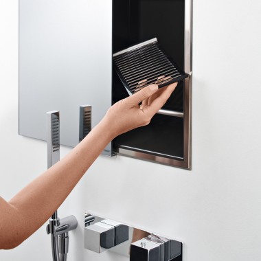 Main de femme positionnant une étagère dans la boîte de rangement de recoin de la douche (© Geberit)