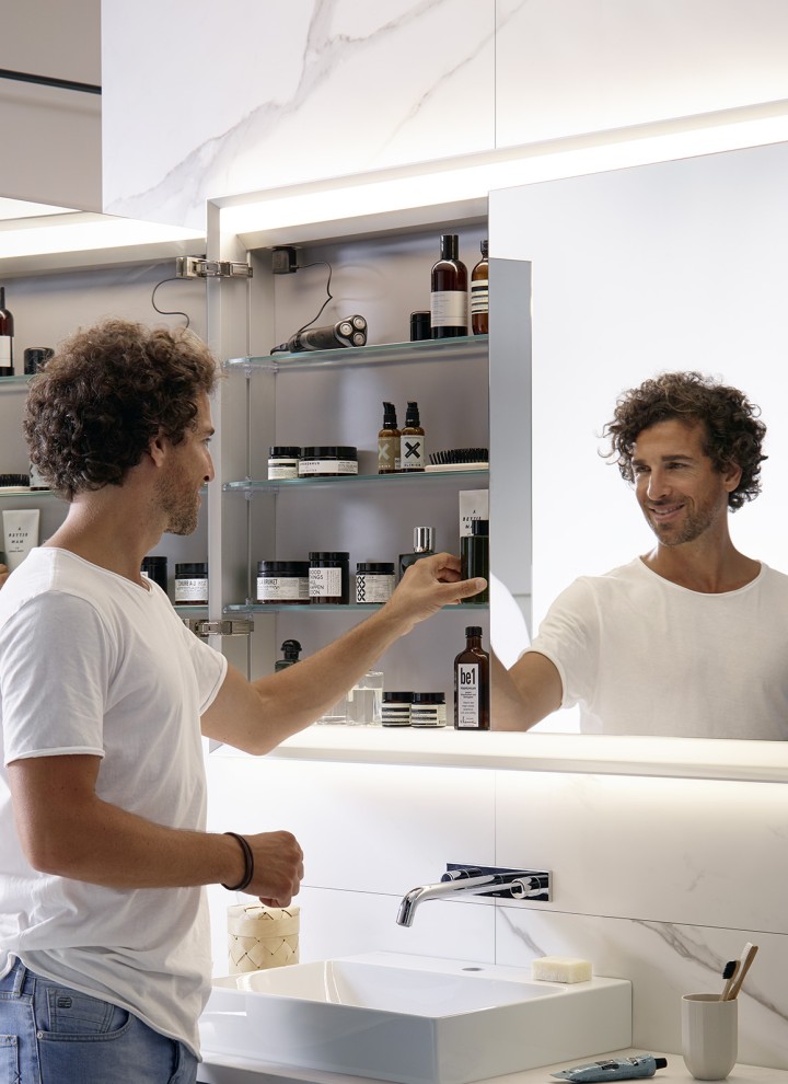 Homme dans une salle de bains équipée d’une armoire de toilette Geberit ONE Homme dans une salle de bains équipée d’une armoire de toilette Geberit ONE