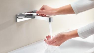 Une femme ouvre le robinet et teste l’intensité et la température du jet d’eau