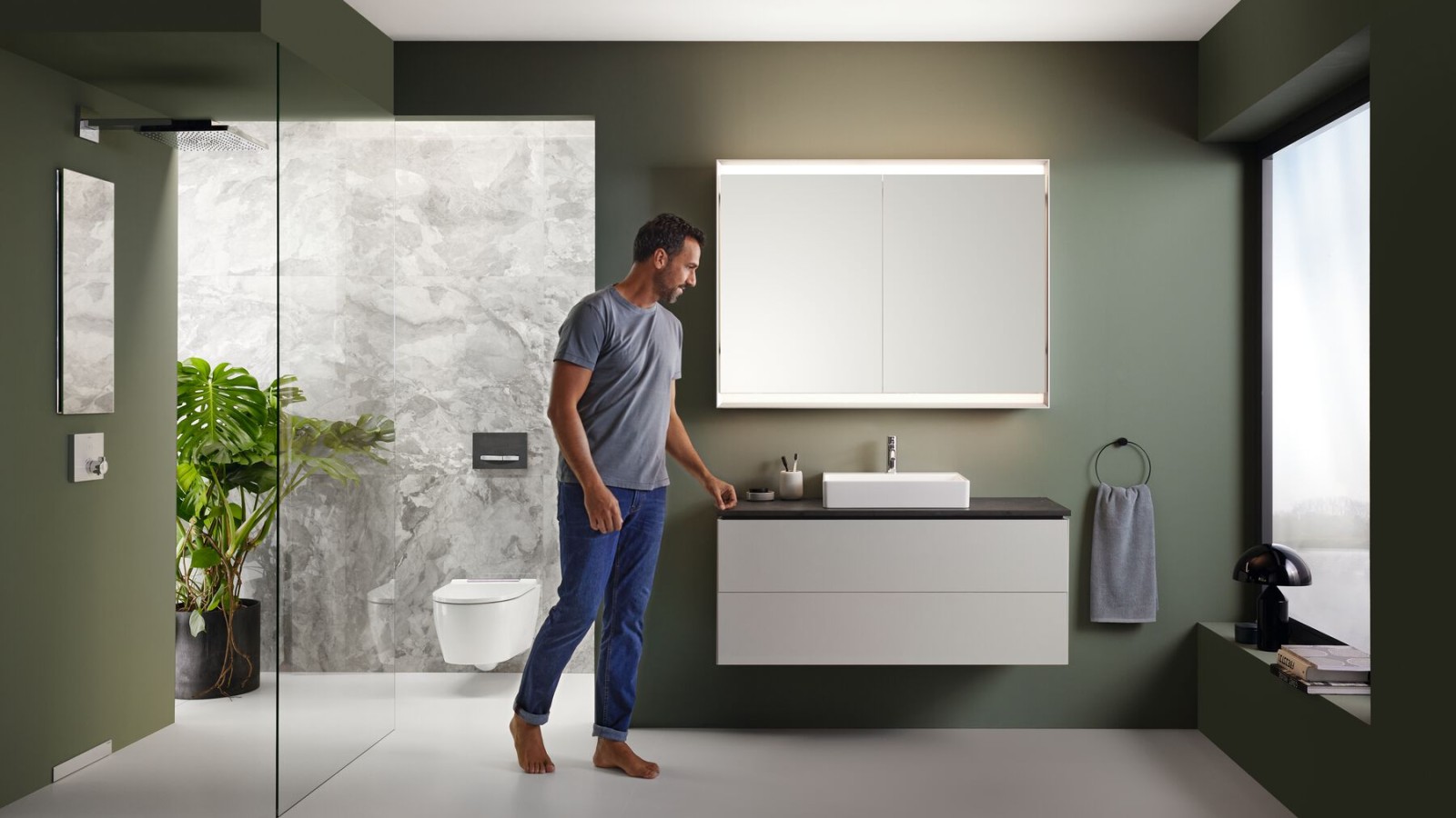 A man stands in a bathroom with high-quality furniture from the Geberit ONE series A man stands in a bathroom with high-quality furniture from the Geberit ONE series