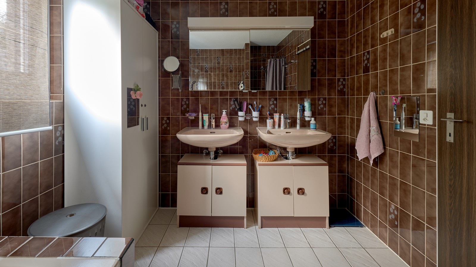 Salle de bains avec carrelage brun et deux lavabos