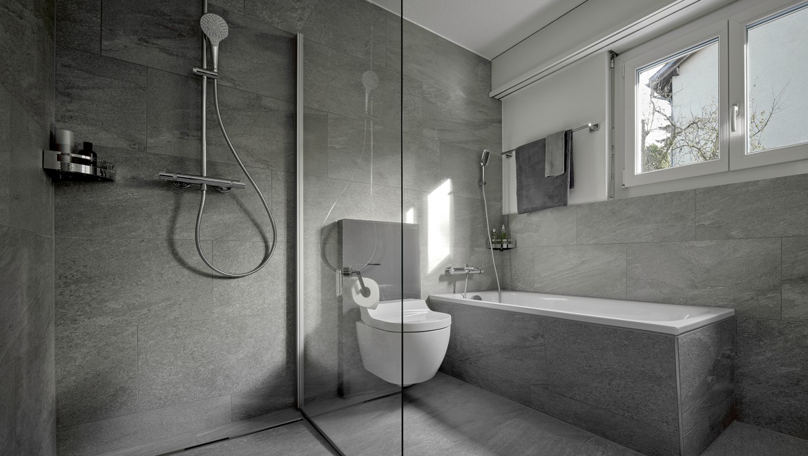 A shower toilet between a floor-standing shower and a bathtub