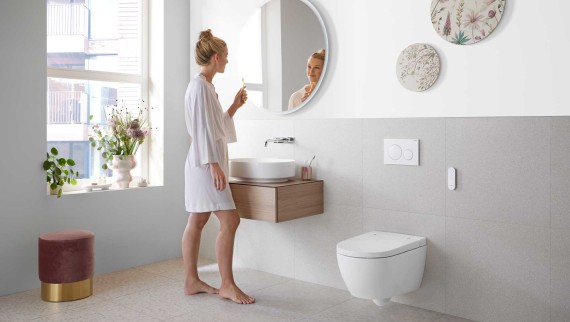 Femme dans une salle de bains blanche avec meubles et céramiques