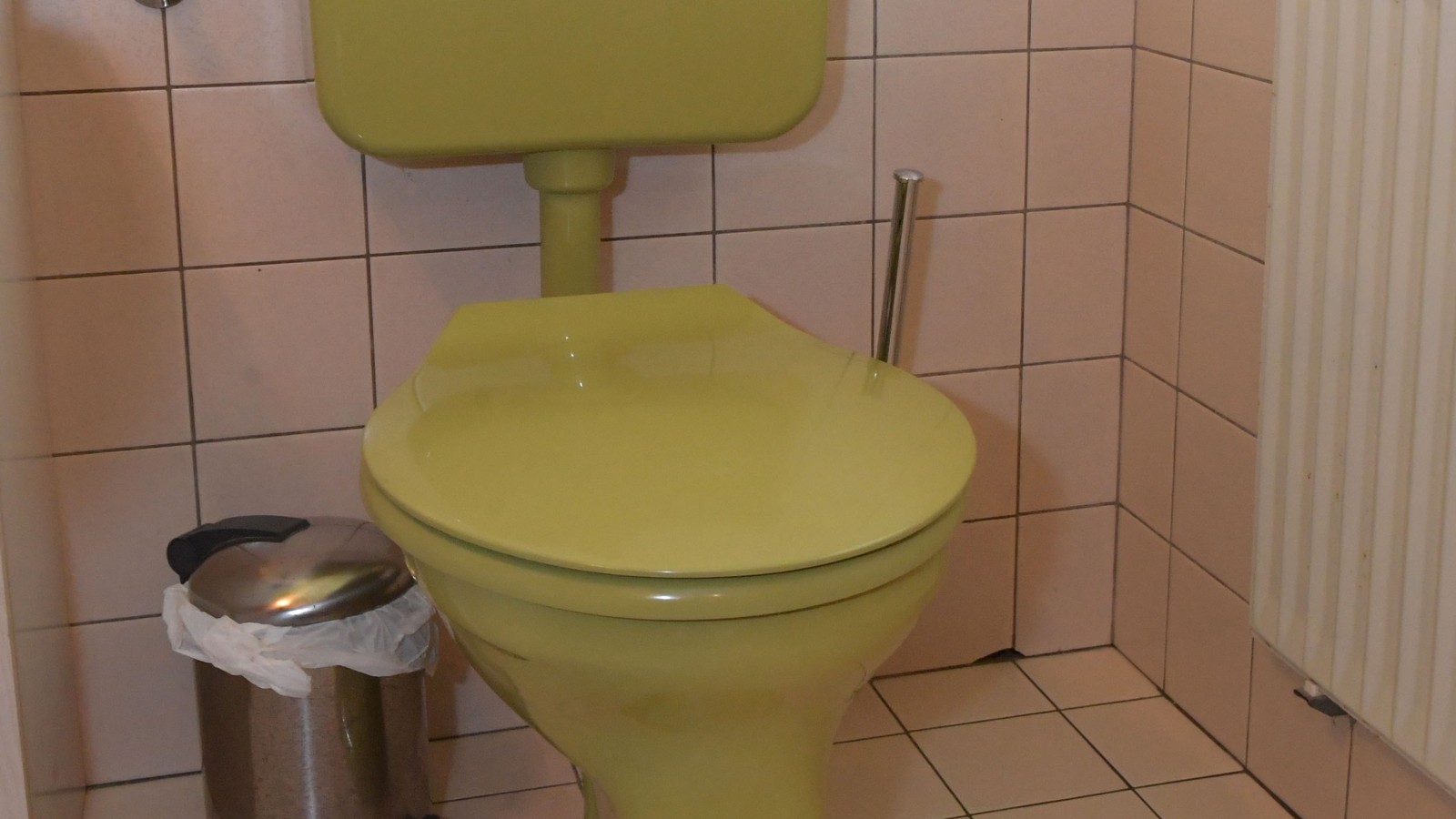 L’ancien WC avec réservoir apparent dans la salle de bains d’invités L’ancien WC avec réservoir apparent dans la salle de bains d’invités