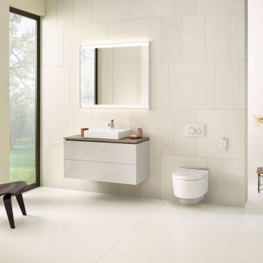 Salle de bains beige avec armoire de toilette, meuble bas, plaque de déclenchement et céramiques sanitaires de Geberit