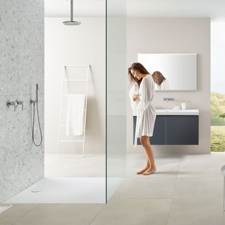Woman in bathroom with walk-in shower and Geberit Olona shower tray Woman in bathroom with walk-in shower and Geberit Olona shower tray