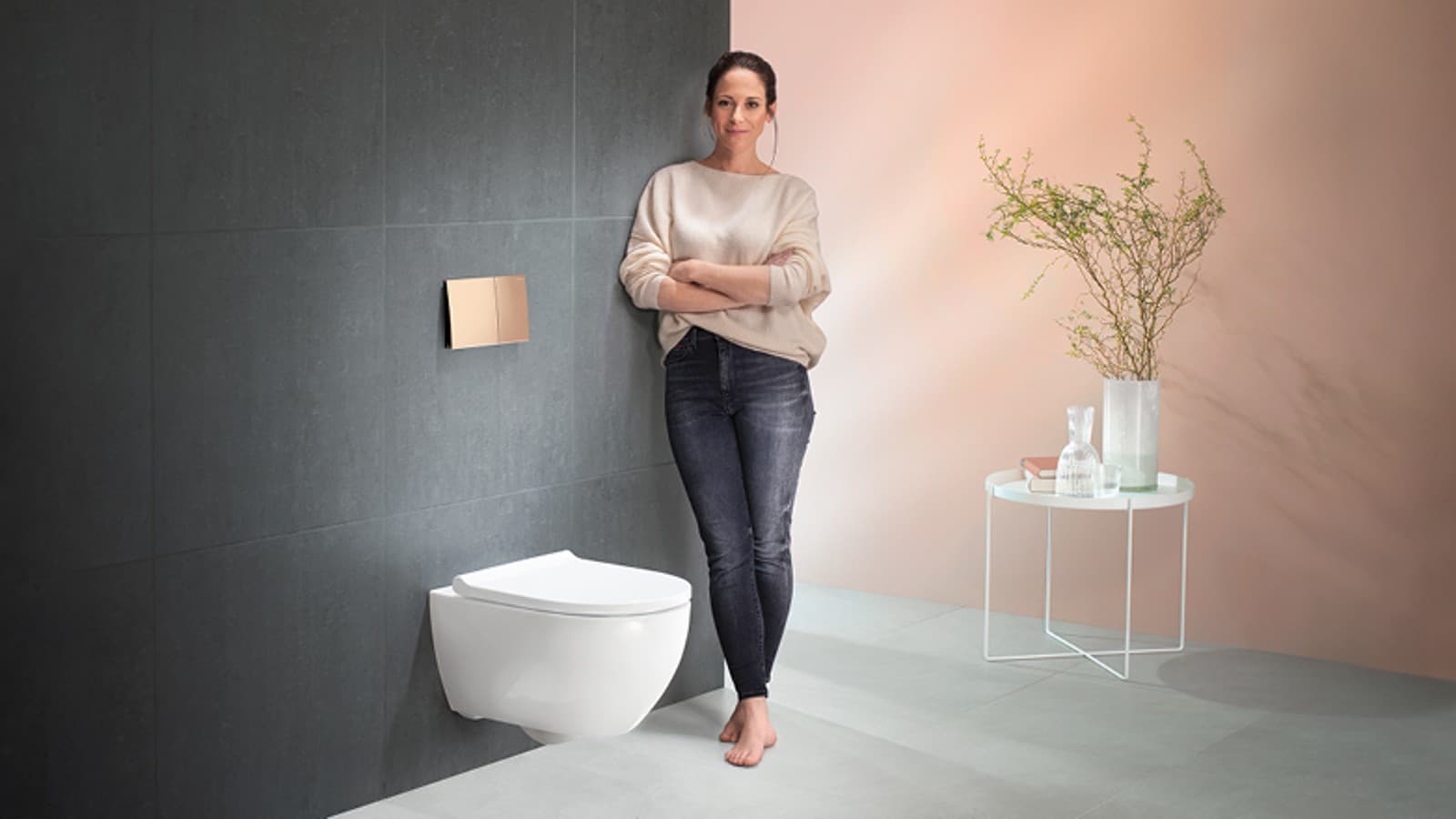 Une femme satisfaite à côté de ses toilettes Geberit Acanto Une femme satisfaite à côté de ses toilettes Geberit Acanto